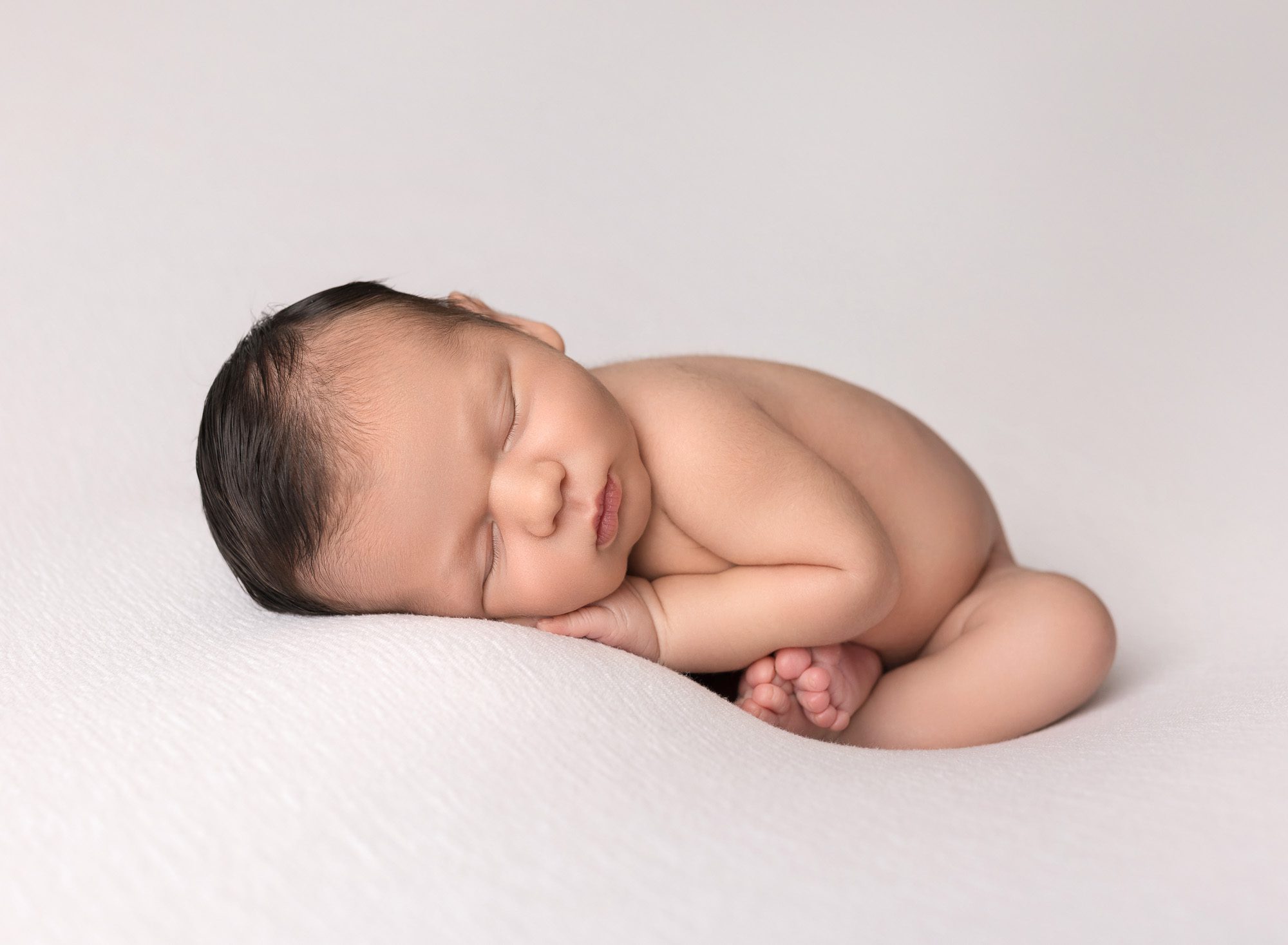 Baby boy is lying on tummy. The baby boy poses and plays with a pacifier.  Stock Photo | Adobe Stock
